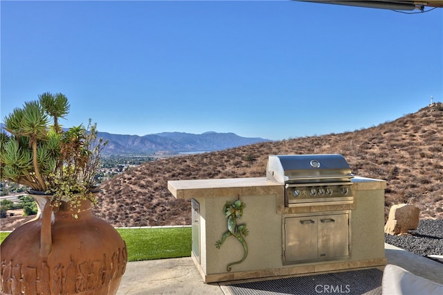 exterior space featuring exterior kitchen, a mountain view, and grilling area