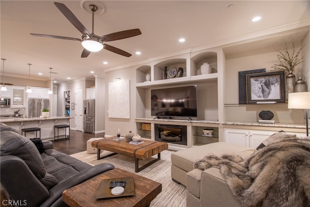 living room featuring ornamental molding, light wood-type flooring, and ceiling fan