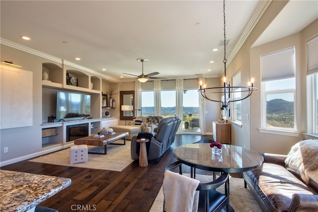 living room featuring crown molding, a mountain view, hardwood / wood-style flooring, and ceiling fan with notable chandelier