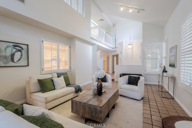 living room featuring light tile patterned floors, a towering ceiling, a wealth of natural light, and track lighting