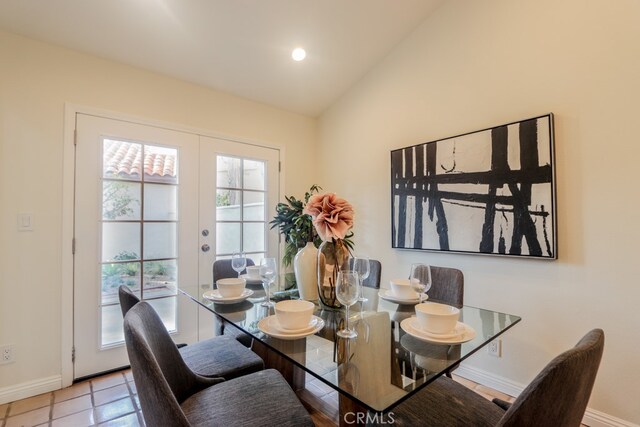 dining space with french doors, light tile patterned floors, and lofted ceiling