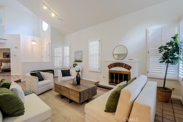 living room with high vaulted ceiling, a fireplace, and light tile patterned floors