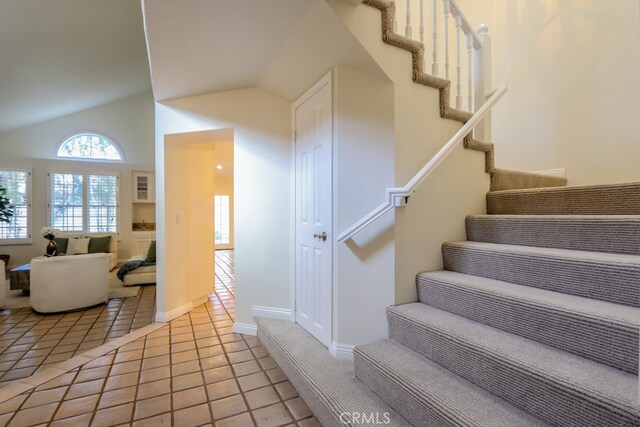 stairway with tile patterned floors and lofted ceiling