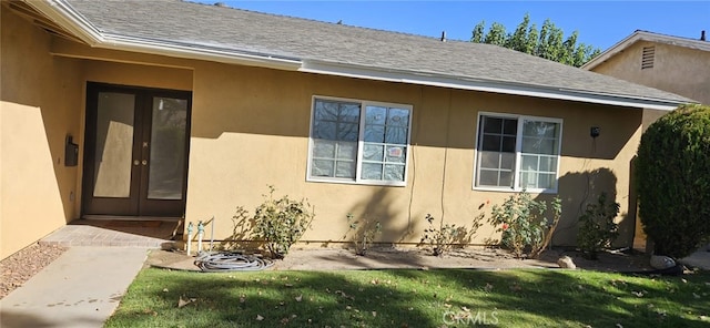 view of exterior entry featuring a lawn and french doors