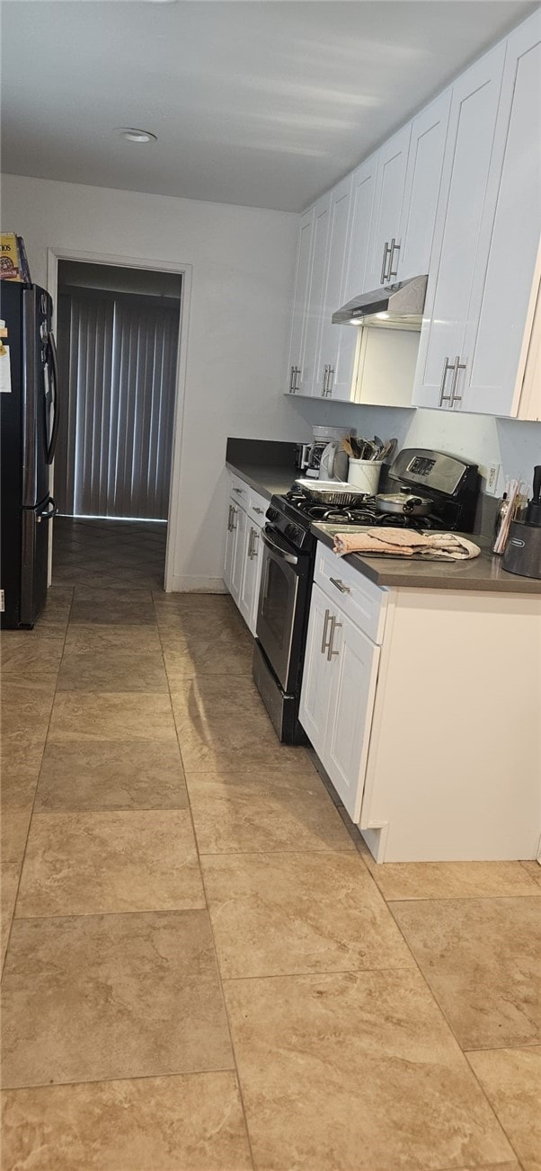 kitchen with gas stove, black fridge, and white cabinets