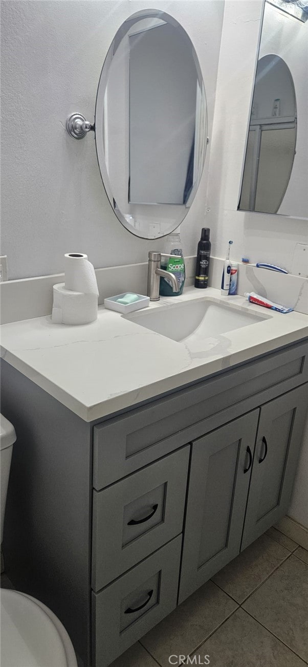 bathroom featuring tile patterned flooring, vanity, and toilet