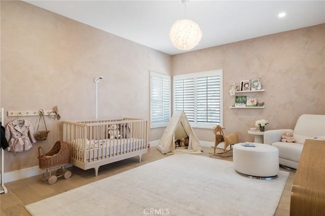 bedroom featuring hardwood / wood-style flooring and a crib