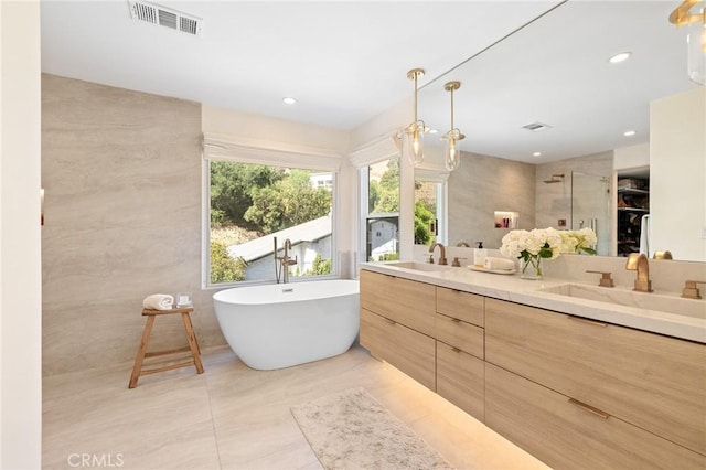 bathroom with tile patterned floors, shower with separate bathtub, tile walls, vanity, and a notable chandelier