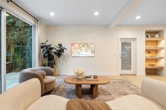 sitting room with built in shelves, wood-type flooring, and beamed ceiling