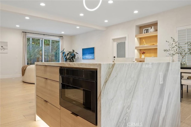 kitchen with light hardwood / wood-style flooring, built in features, oven, and light brown cabinets