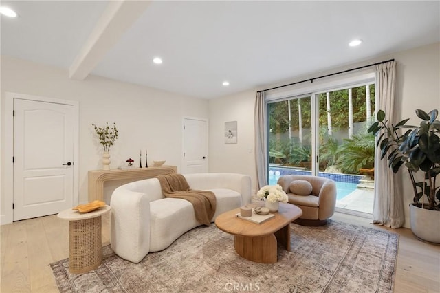 living area with beamed ceiling and light wood-type flooring