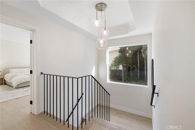 staircase with wood-type flooring and a tray ceiling