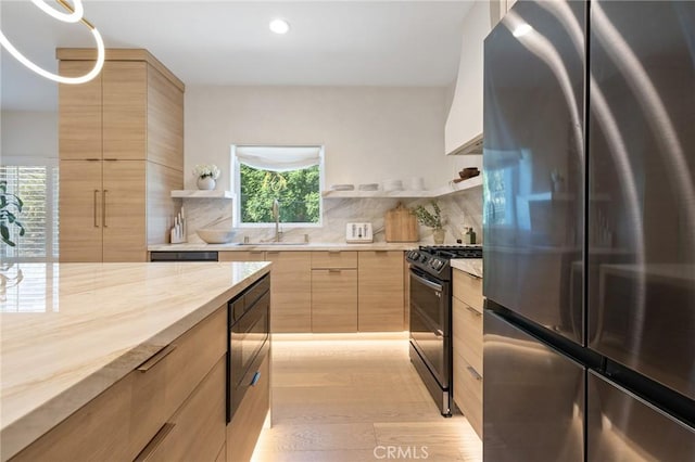 kitchen with black gas range oven, wood counters, stainless steel refrigerator, built in microwave, and sink