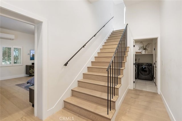 stairs featuring hardwood / wood-style flooring, a wall mounted AC, and separate washer and dryer