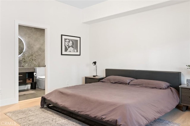 bedroom featuring ensuite bathroom and light wood-type flooring