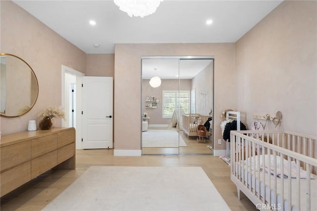 bedroom with a crib, light hardwood / wood-style flooring, and a closet