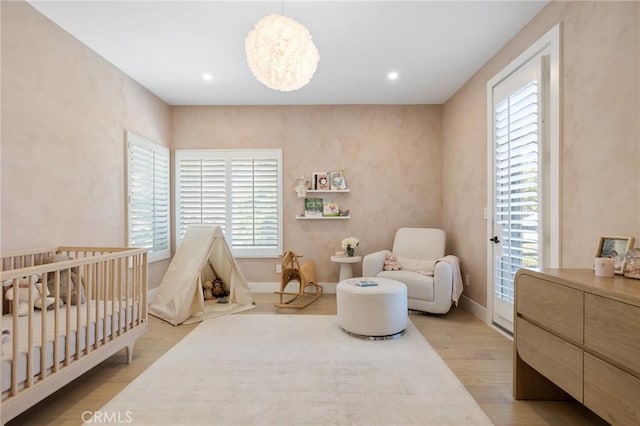 bedroom with a nursery area and light wood-type flooring