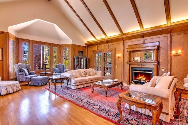 living room with beamed ceiling, hardwood / wood-style flooring, high vaulted ceiling, and wood walls