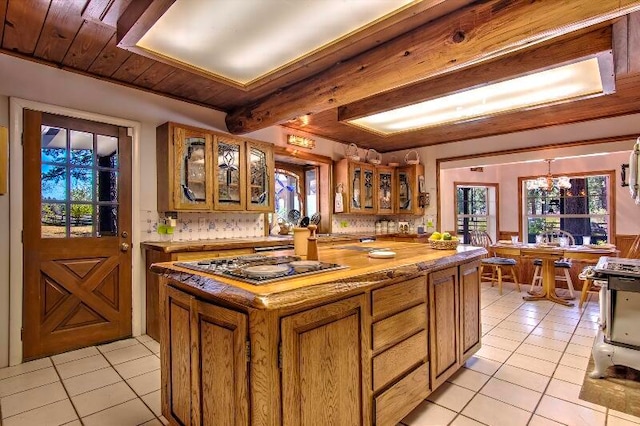 kitchen with decorative backsplash, light tile patterned flooring, a kitchen island, and appliances with stainless steel finishes