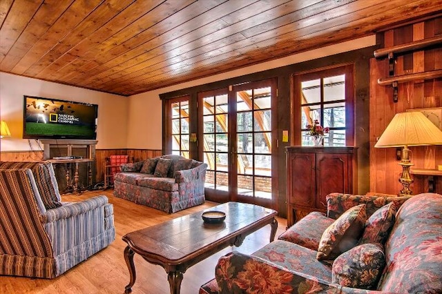 living room featuring light hardwood / wood-style flooring, wood ceiling, wood walls, and a wealth of natural light