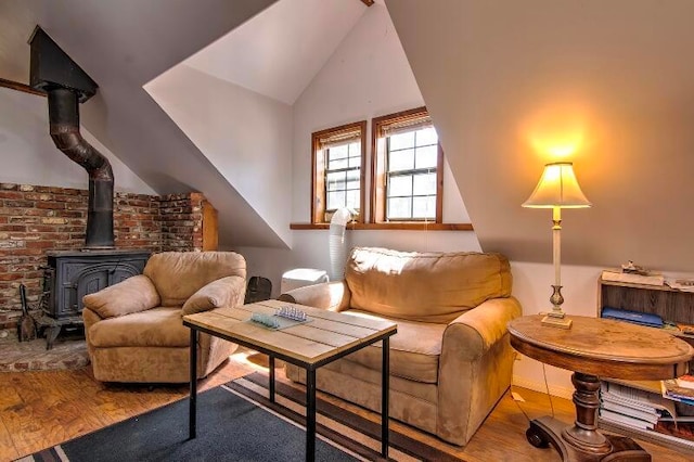 living area featuring lofted ceiling, hardwood / wood-style floors, and a wood stove