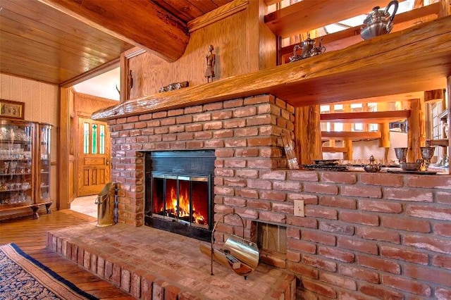 living room with beam ceiling, hardwood / wood-style flooring, and a brick fireplace