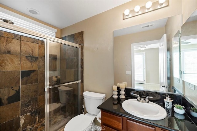 bathroom featuring vanity, a healthy amount of sunlight, a shower with shower door, and toilet