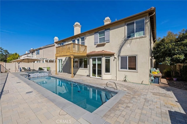 rear view of house with a balcony, a patio area, and a fenced in pool