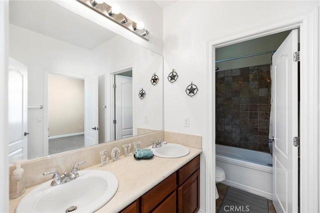 full bathroom featuring vanity, tiled shower / bath combo, and toilet