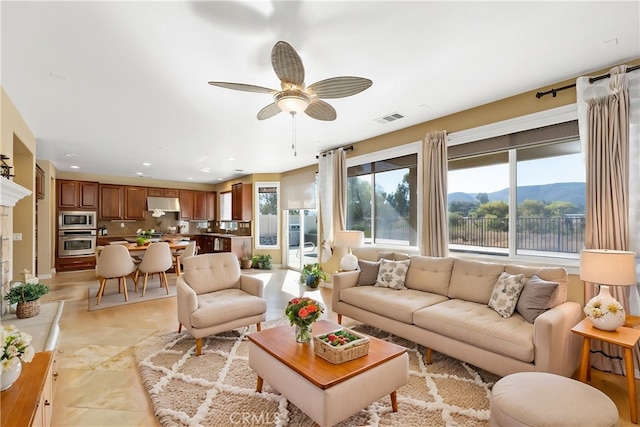 living room with a wealth of natural light, a mountain view, and ceiling fan