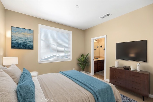 bedroom featuring ensuite bath and light carpet