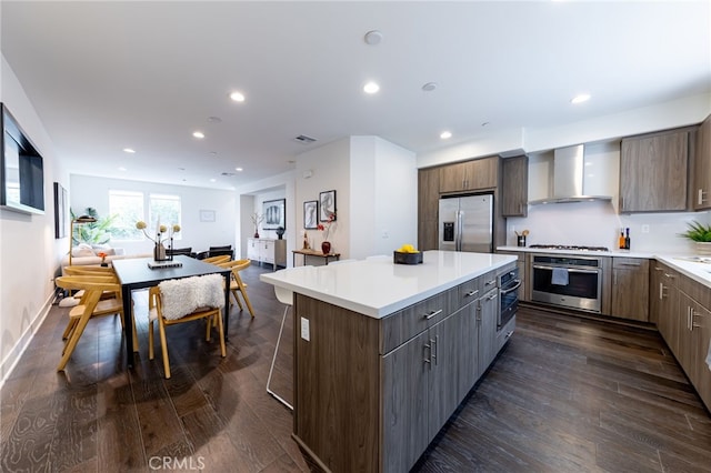 kitchen with a kitchen island, wall chimney exhaust hood, dark hardwood / wood-style floors, and appliances with stainless steel finishes