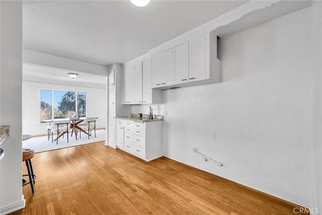 kitchen featuring light stone countertops, white cabinetry, and light hardwood / wood-style flooring