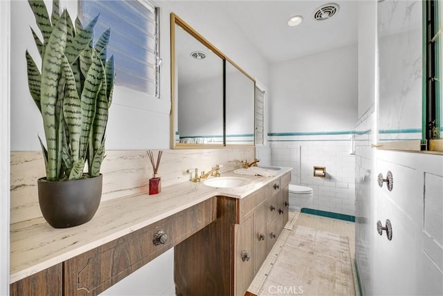 bathroom featuring toilet, vanity, and tile walls