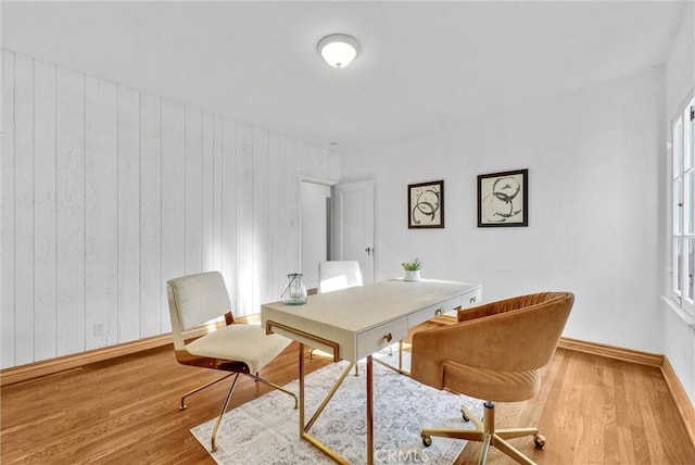 office with wood walls and light hardwood / wood-style floors