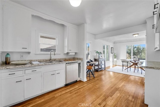 kitchen featuring white cabinetry, light hardwood / wood-style floors, dishwasher, light stone countertops, and sink