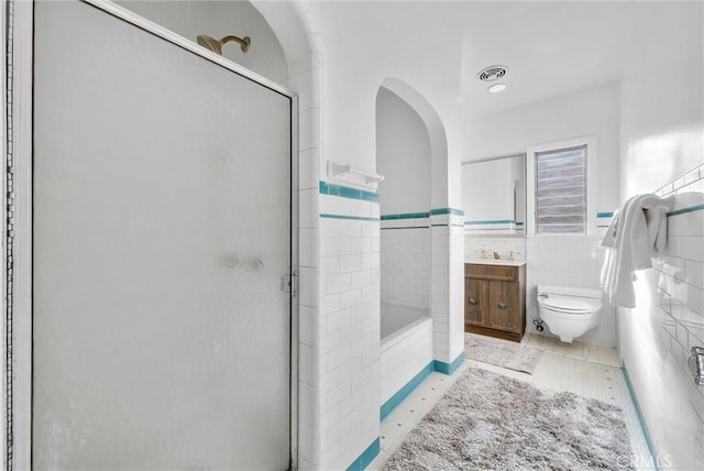 bathroom featuring toilet, tile walls, an enclosed shower, and vanity