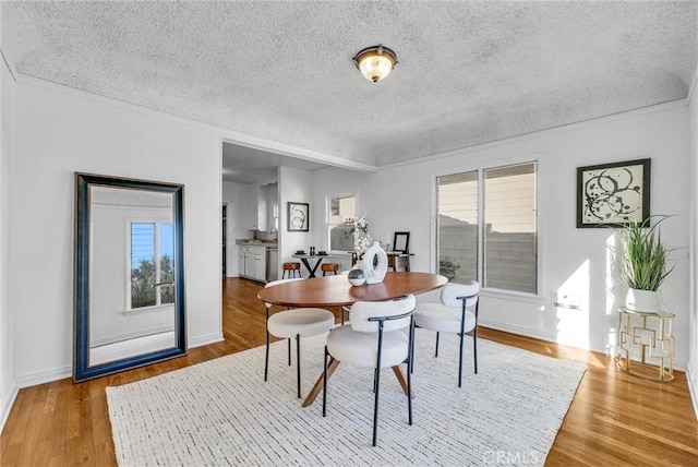 dining space featuring a healthy amount of sunlight, a textured ceiling, and hardwood / wood-style floors