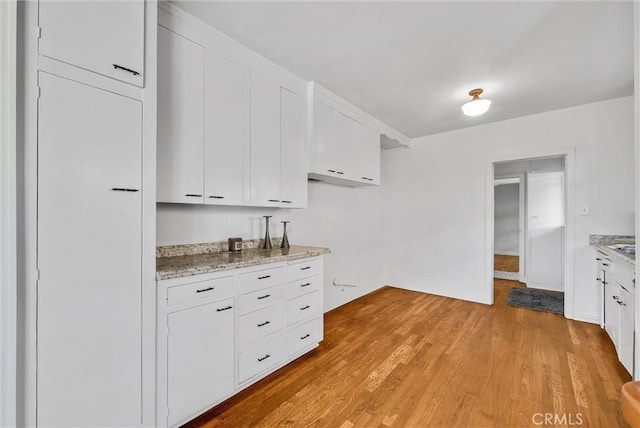 kitchen featuring light hardwood / wood-style floors, white cabinets, and light stone counters