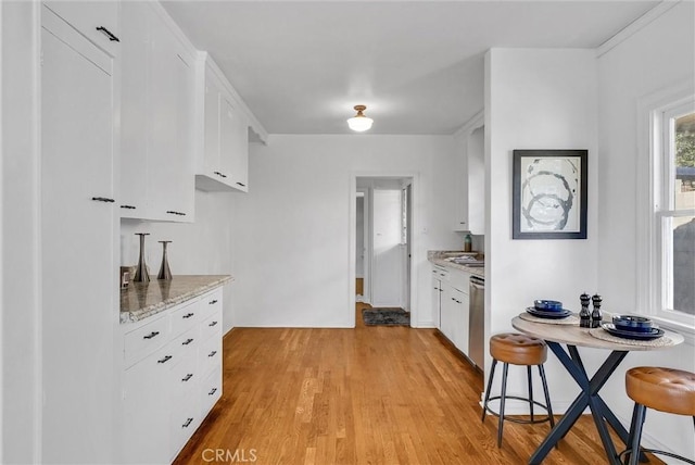 kitchen with light hardwood / wood-style floors, light stone counters, stainless steel dishwasher, white cabinets, and a breakfast bar