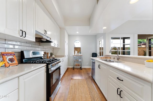 kitchen featuring decorative backsplash, stainless steel appliances, sink, light hardwood / wood-style flooring, and white cabinets