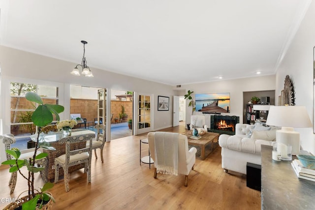 living room featuring an inviting chandelier, crown molding, and light hardwood / wood-style flooring