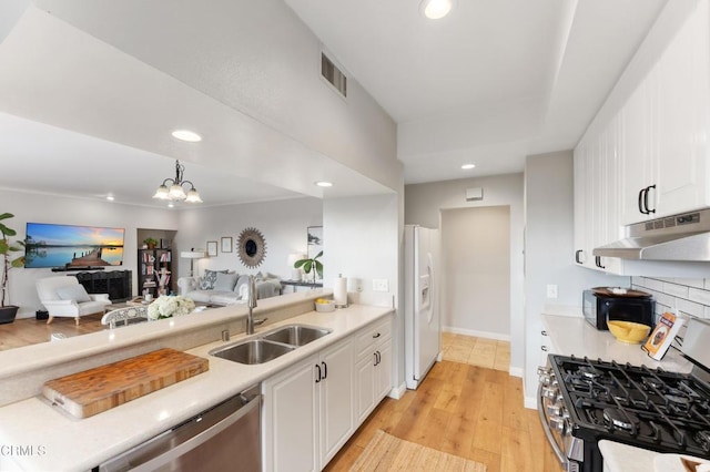 kitchen with appliances with stainless steel finishes, sink, a chandelier, white cabinets, and light hardwood / wood-style floors