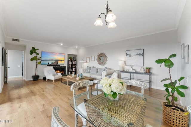 living room featuring light hardwood / wood-style floors, ornamental molding, and a notable chandelier