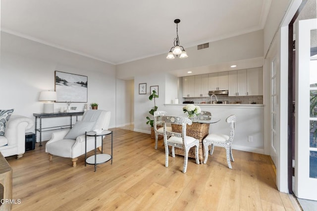 dining space featuring a notable chandelier, crown molding, and light hardwood / wood-style flooring