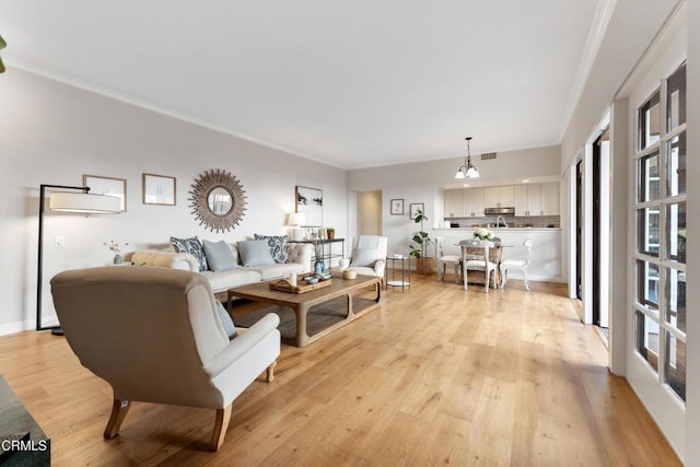 living room featuring a notable chandelier, crown molding, and light hardwood / wood-style flooring