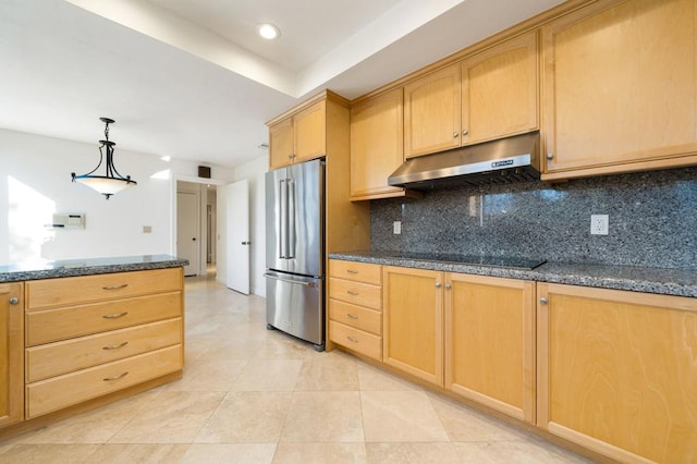 kitchen with stainless steel refrigerator, dark stone countertops, black cooktop, decorative backsplash, and light brown cabinetry