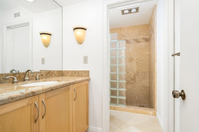 bathroom with tile patterned flooring, a tile shower, and vanity