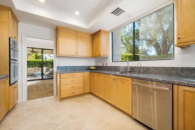 kitchen with dark stone countertops, sink, stainless steel appliances, and a tray ceiling