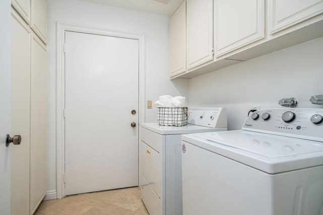 washroom with cabinets, light tile patterned floors, and washing machine and clothes dryer